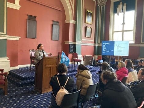 A woman is delivering a powerful speech to a diverse audience about the law of society.