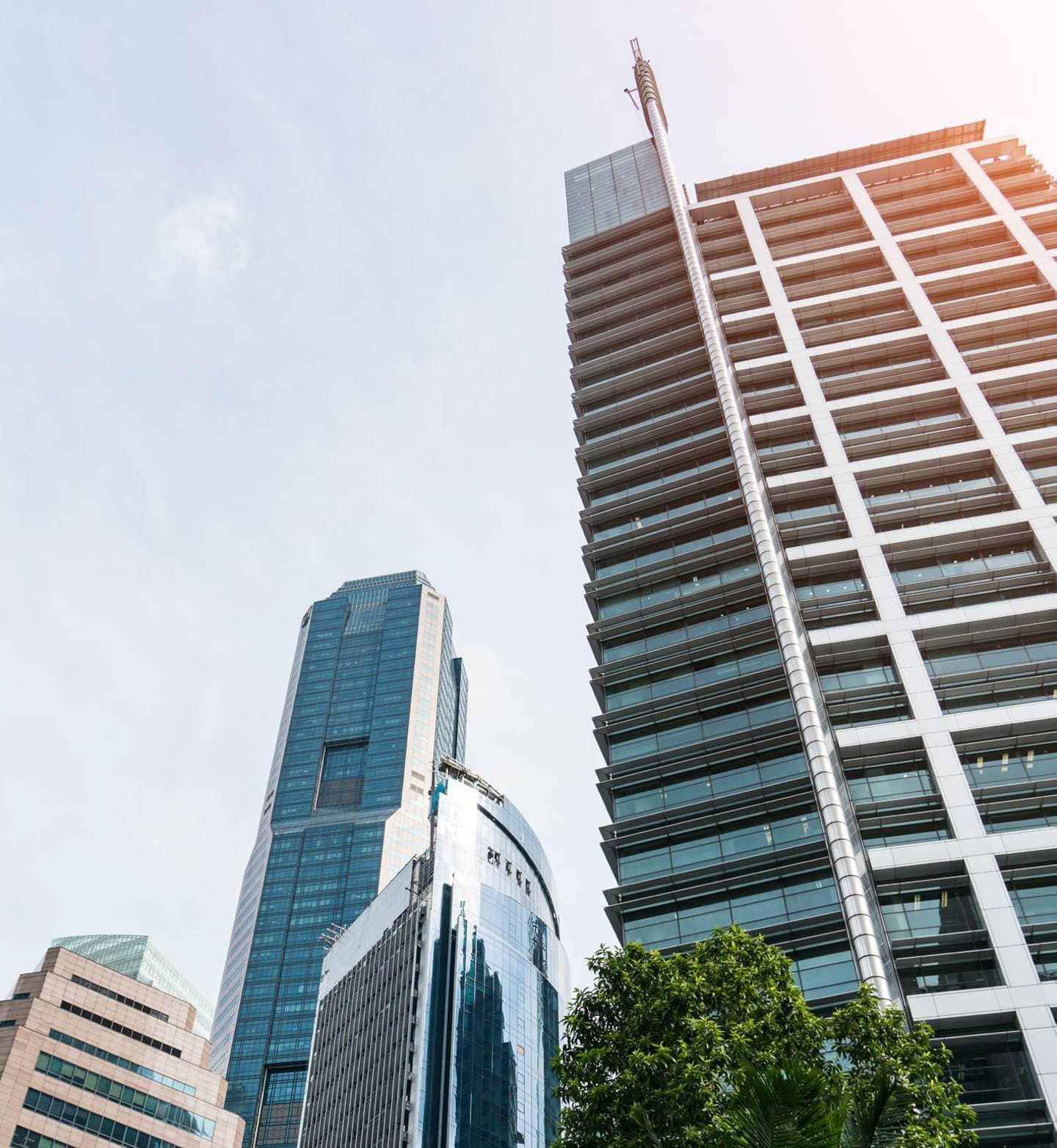 The city skyline in Singapore is made up of tall buildings against a blue sky.