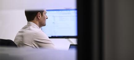 A man is providing guidance in Asset Management and Investment Funds while sitting at a desk and using a computer.