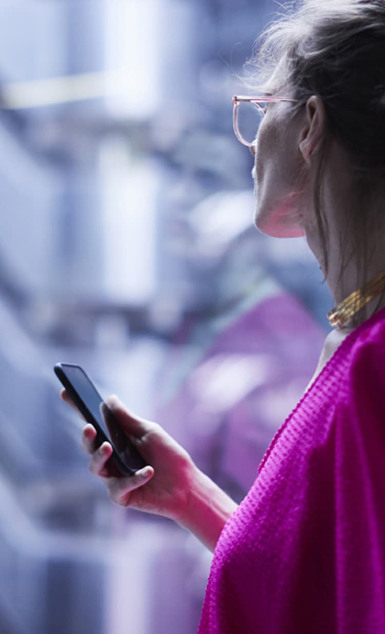 A financial legal advisor in a pink dress while holding her cell phone.